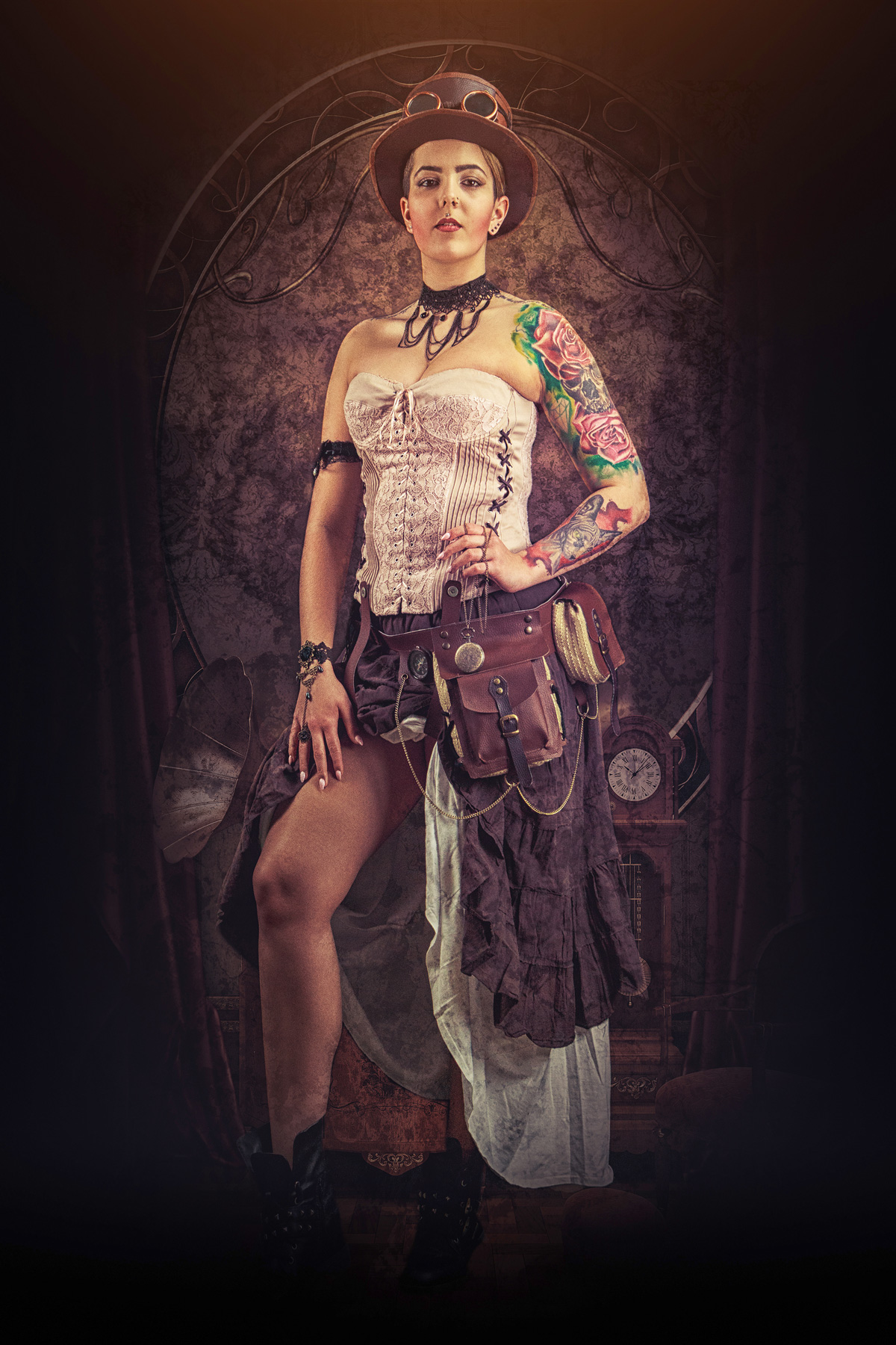 A full-body steampunk portrait of a woman in a pale pink lace corset and ruffled brown skirt, wearing a top hat with goggles, leather utility pouches with a pocket watch, and featuring colorful rose tattoos on her arm.